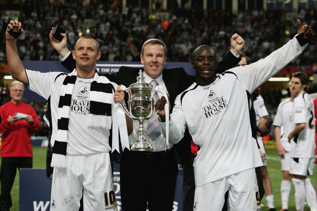CARDIFF, UNITED KINGDOM - APRIL 02:  Lee Trundle (L), manager Kenny Jacket (C), and Adebayo Akinfenwa of Swansea City celebrate after Swansea City's 2-1 victory in The Football League Trophy Final match between Carlisle United and Swansea City, at the Millennium Stadium on April 2, 2006 in Cardiff, Wales.  (Photo by Paul Gilham/Getty Images)