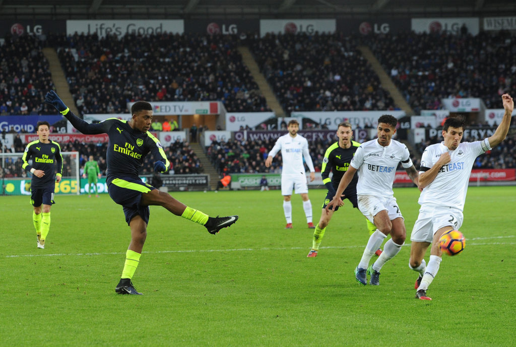 SWANSEA, WALES - JANUARY 14:  Alex Iwobi scores Arsenal's 2nd goal under pressure from Jack Cork of Swansea during the Premier League match between Swansea City and Arsenal at Liberty Stadium on January 14, 2017 in Swansea, Wales.  (Photo by David Price/Arsenal FC via Getty Images)